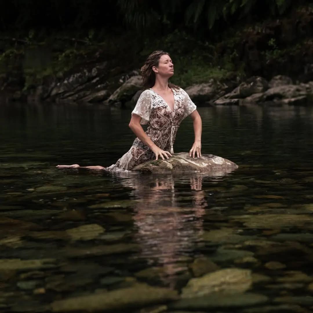 Alexandra sitting beside still water in a natural setting.