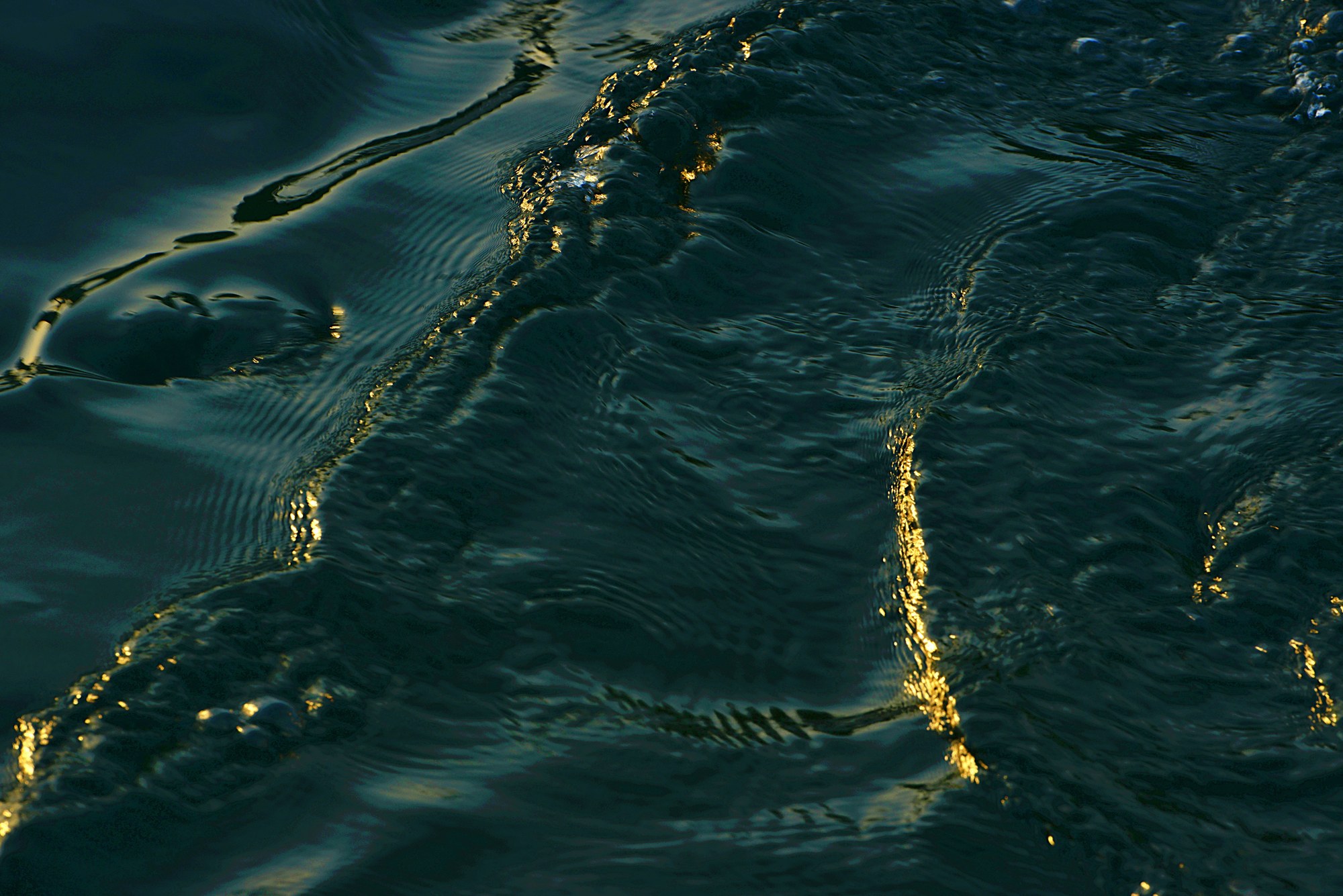 Golden lines of light reflected in deep blue water.